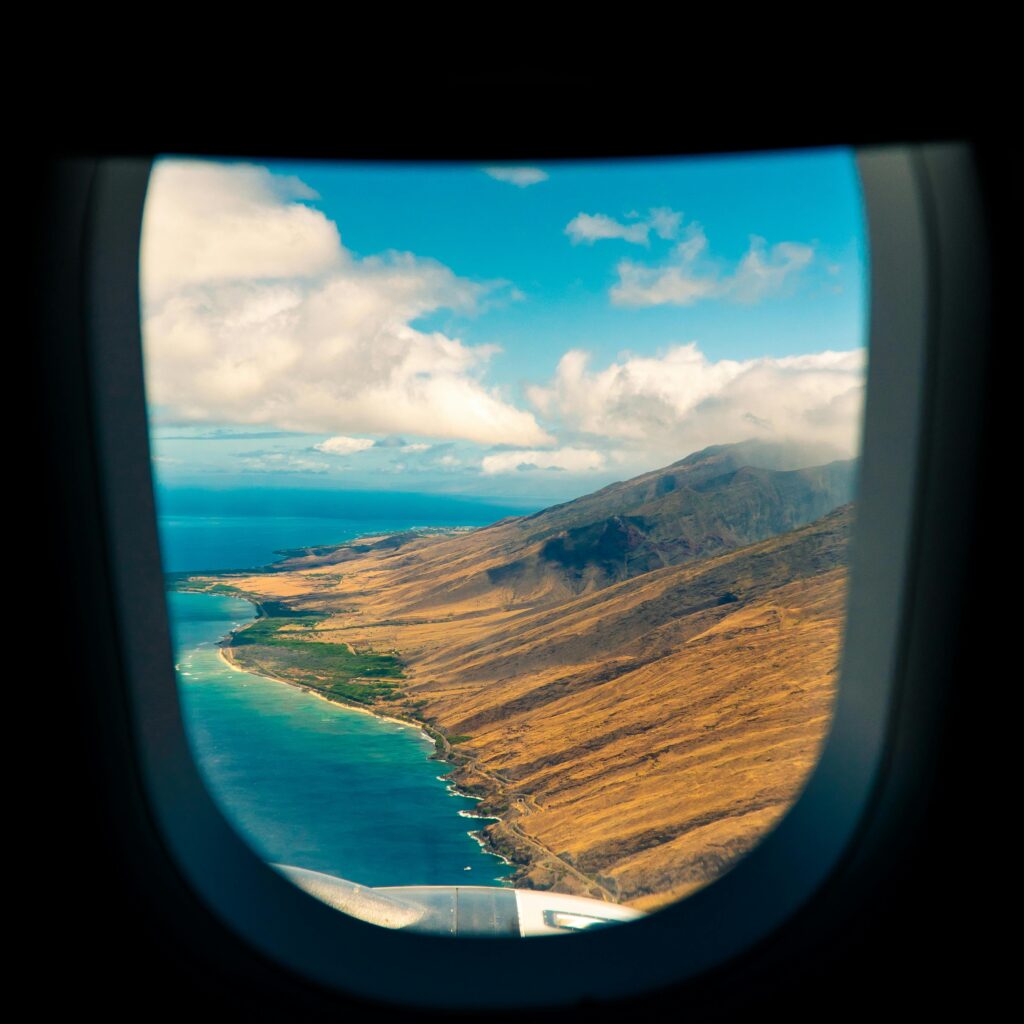 Breathtaking view of Maui's coastline from an airplane window showcasing mountains and ocean.