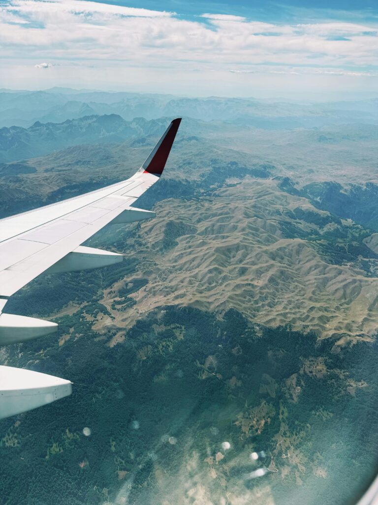 A scenic aerial view from an airplane wing over mountainous terrain on a clear day.