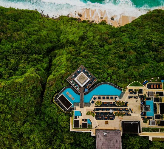 Stunning aerial shot of a luxury resort in Bali, surrounded by lush greenery and ocean view.