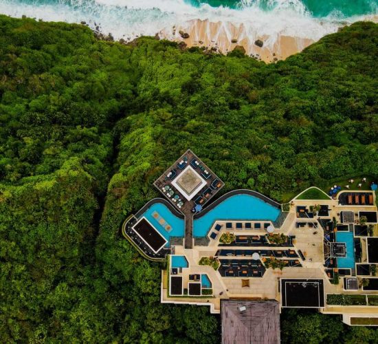 Stunning aerial shot of a luxury resort in Bali, surrounded by lush greenery and ocean view.