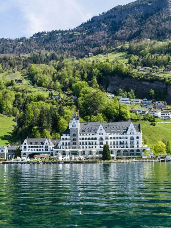 Stunning lakeside view of the Grand Hotel Vitznau against the Swiss Alps, reflecting in Lake Lucerne.